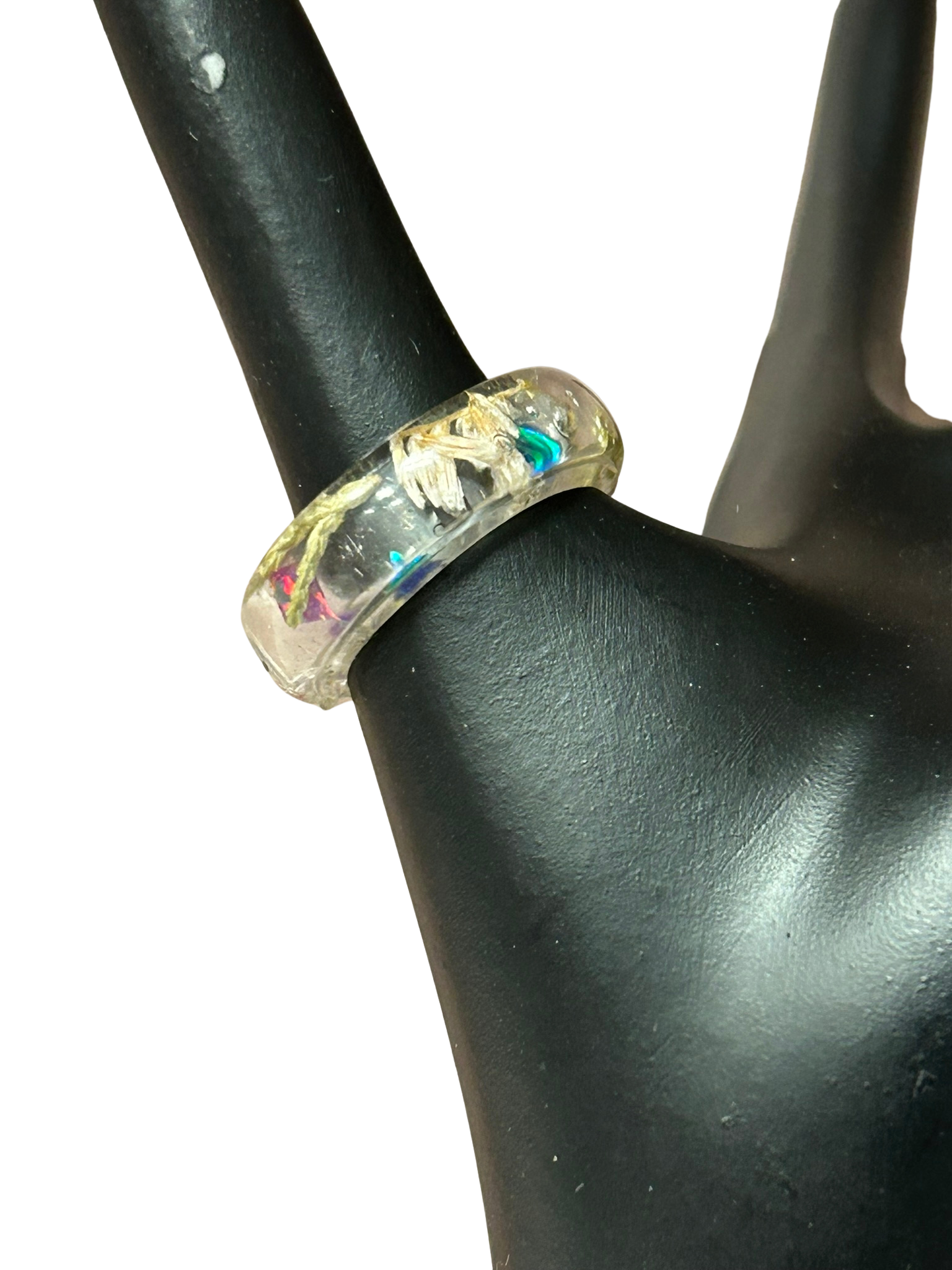 Ring with a multicolored stone on a black mannequin hand against a white background