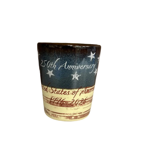 Ceramic shot glass with stars, blue top half and white and red strips on the bottom half with '250th Anniversary United States of America' 