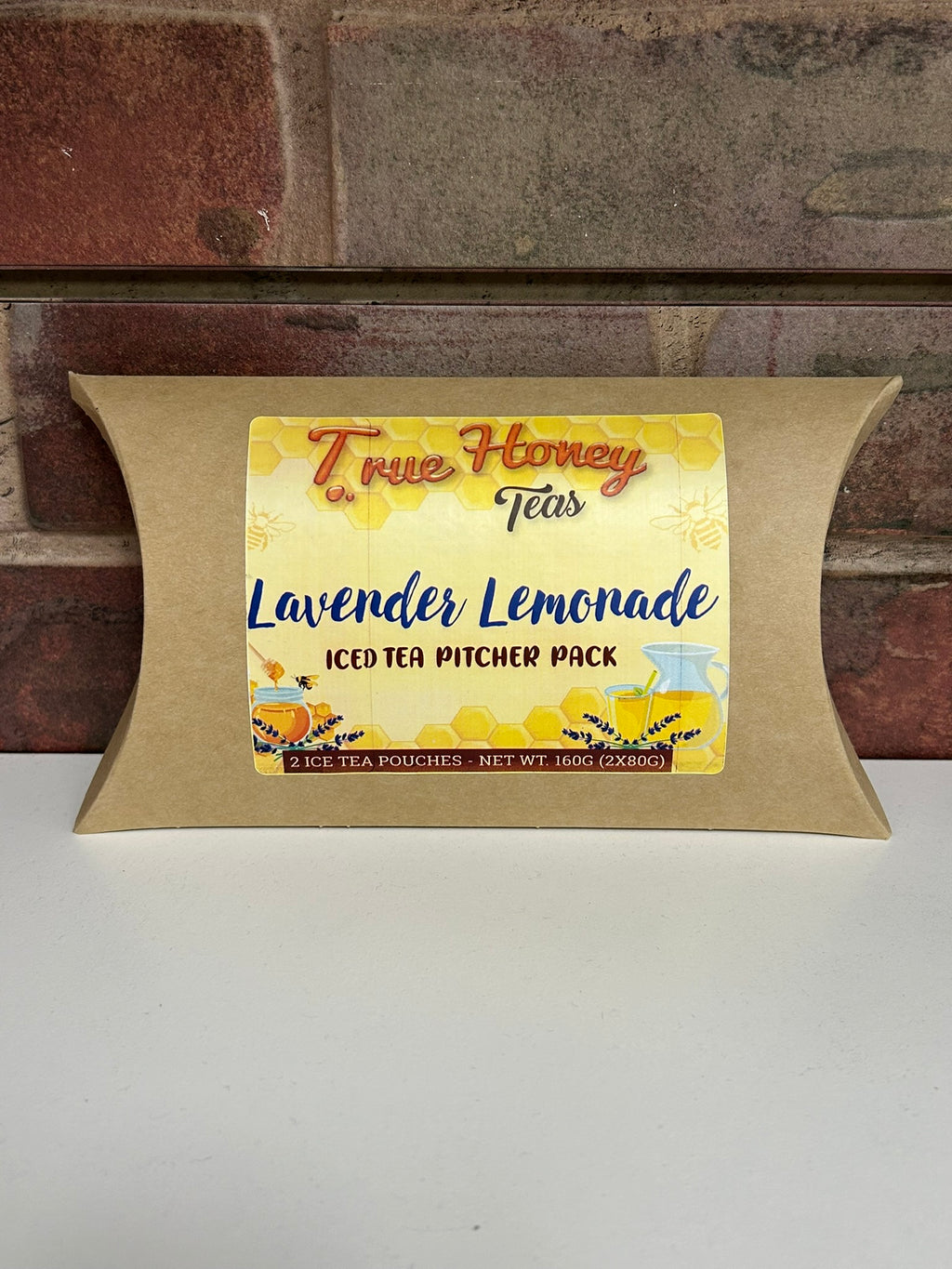 Packaged iced tea with 'True Honey Lavender Lemonade' label against a brick wall background