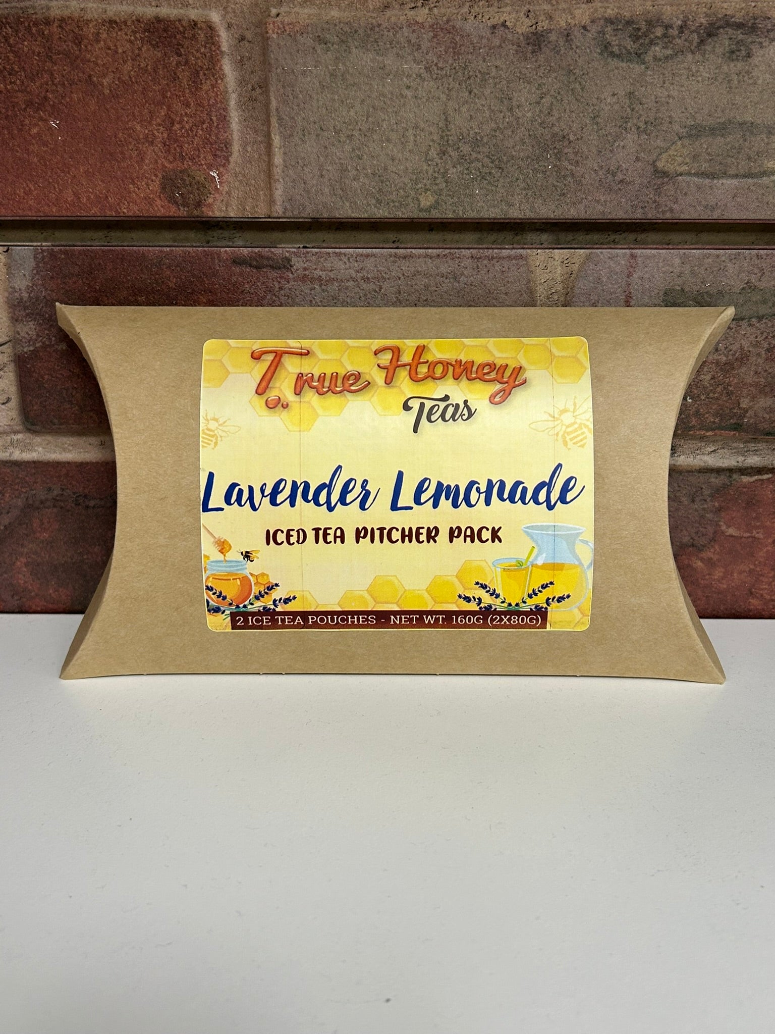 Packaged iced tea with 'True Honey Lavender Lemonade' label against a brick wall background